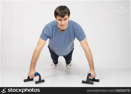 thirty young athletic man does physical exercises. Athlete the highest point at push-ups on legs