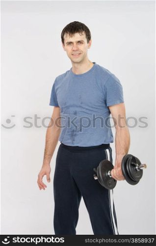thirty young athletic man does physical exercises. Portrait of an athlete with dumbbells in the hands