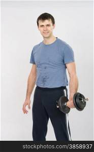 thirty young athletic man does physical exercises. Portrait of an athlete with dumbbells in the hands