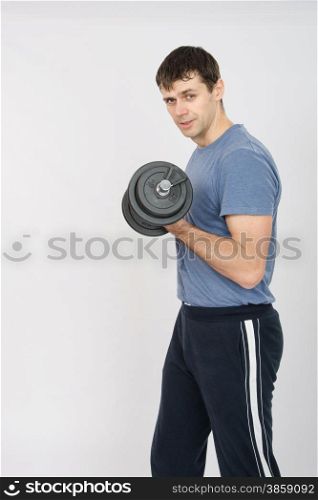 thirty young athletic man does physical exercises. Portrait of an athlete with a dumbbell in your left hand
