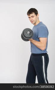 thirty young athletic man does physical exercises. Portrait of an athlete with a dumbbell in your left hand