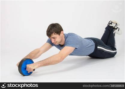 thirty young athletic man does physical exercises. The athlete is pushed by a wheel
