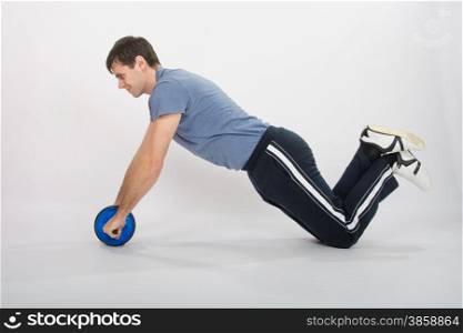 thirty young athletic man does physical exercises. The athlete is pushed from floor to wheel