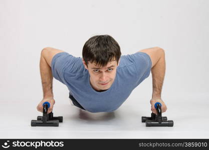 thirty young athletic man does physical exercises. The athlete performs a bench on supports