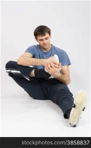 thirty young athletic man does physical exercises. The athlete performs a workout right foot