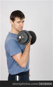 thirty young athletic man does physical exercises. Tired athlete with dumbbells