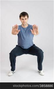 thirty young athletic man does physical exercises. Young athlete performs squats