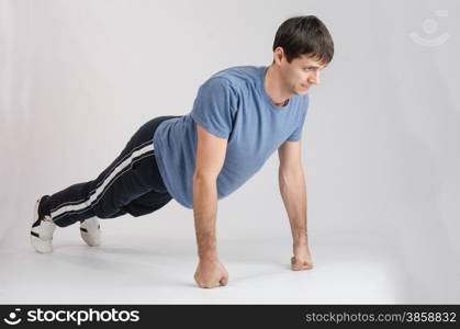 thirty young athletic man does physical exercises. Young guy pushed off the floor with their fists