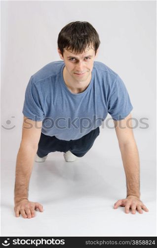 thirty young athletic man does physical exercises. Young guy pushed off the floor