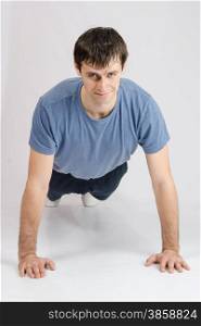 thirty young athletic man does physical exercises. Young guy pushed off the floor