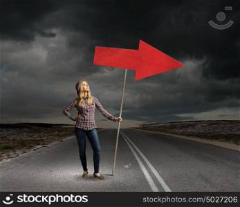 This way. Young girl with arrow signbord in empty room