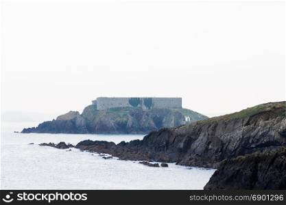 Thorn Island dominated by coastal artillery fort on stormy day. Angle, Pembrokeshire, Wales, United Kingdom. Copyspace above.