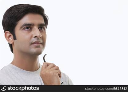 Thought young man holding glasses over white background
