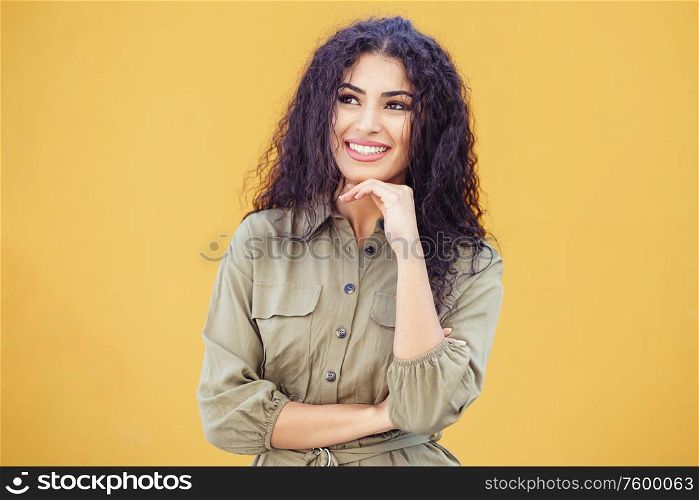 Thoughtful Arab Woman with curly hair in urban background. Young Arab Woman with curly hair outdoors