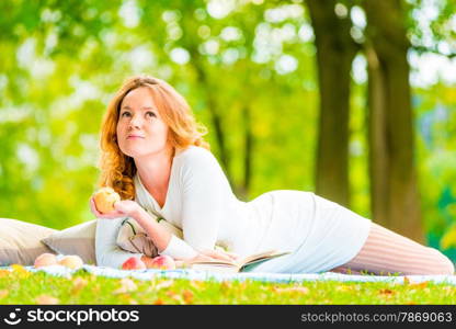 thoughtful beautiful girl with ripe apple in the park