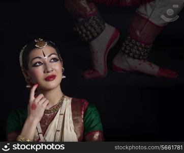 Thoughtful Bharatanatyam dancer over black background