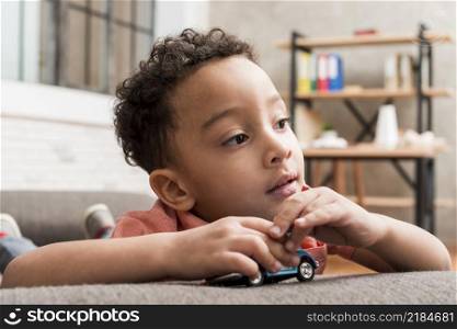 thoughtful black boy playing with toy car