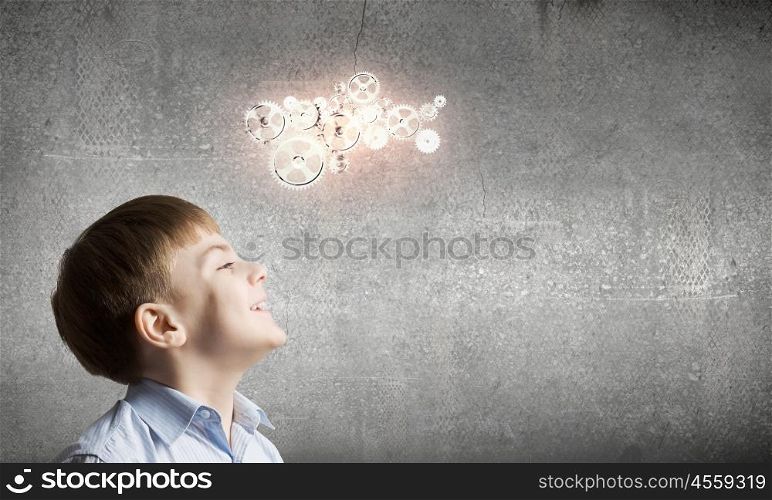 Thoughtful boy. Cute boy of school age looking up at gears mechanism