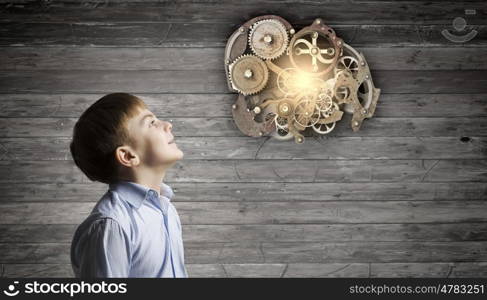 Thoughtful boy. Cute boy of school age looking up at gears mechanism