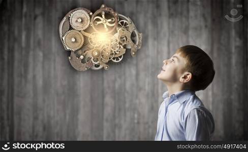 Thoughtful boy. Cute boy of school age looking up at gears mechanism