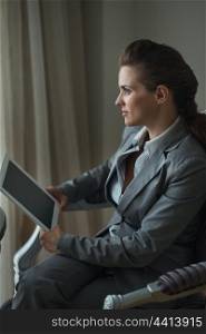Thoughtful business woman holding tablet PC