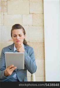 Thoughtful business woman looking in tablet pc