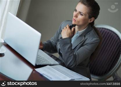 Thoughtful business woman sitting at desk in hotel room