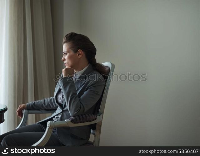 Thoughtful business woman sitting in hotel room