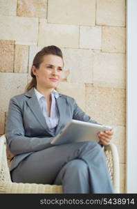 Thoughtful business woman with tablet pc sitting on terrace