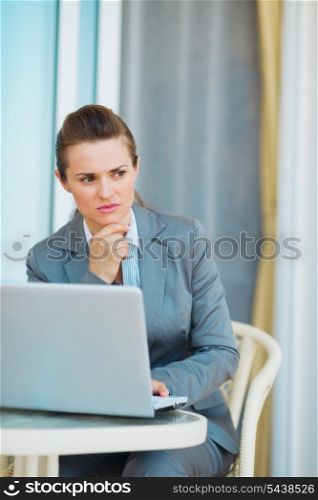Thoughtful business woman working with laptop on terrace