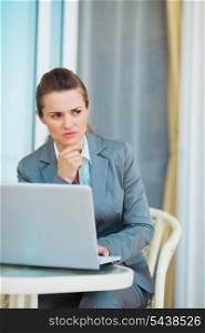Thoughtful business woman working with laptop on terrace