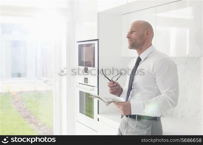 Thoughtful businessman holding newspaper at home