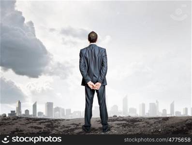 Thoughtful businessman. Rear view of businessman standing against urban scene