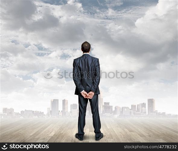 Thoughtful businessman. Rear view of businessman standing against urban scene