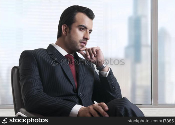 Thoughtful businessman sitting by window in office