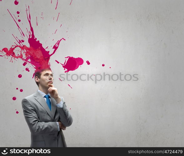 Thoughtful businessman with colorful splashes out of his head. Man with colored head