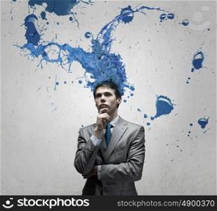 Thoughtful businessman with colorful splashes out of his head. Man with colored head
