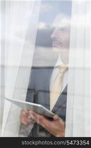 Thoughtful businessman with digital tablet in office