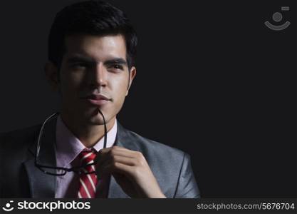 Thoughtful businessman with glasses against black background