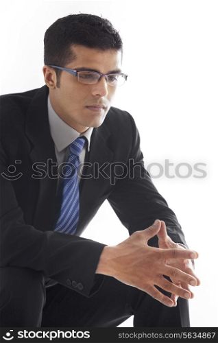 Thoughtful businessman with hands clasped over white background