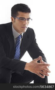 Thoughtful businessman with hands clasped over white background