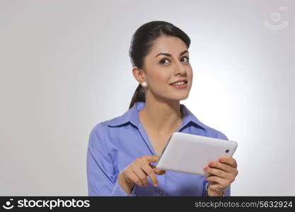 Thoughtful businesswoman holding digital tablet against gray background