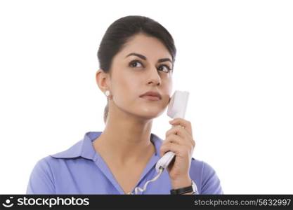 Thoughtful businesswoman holding telephone receiver against white background