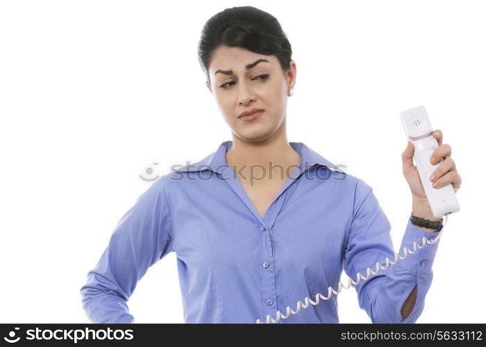 Thoughtful businesswoman holding telephone receiver against white background