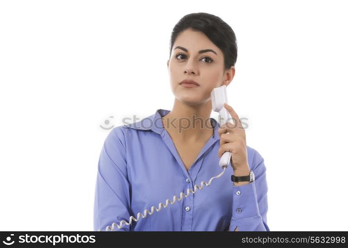 Thoughtful businesswoman holding telephone receiver over white background