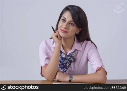 Thoughtful businesswoman leaning on office desk