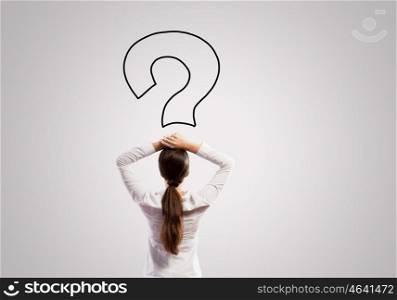 Thoughtful businesswoman. Rear view of businesswoman looking thoughtfully at question mark above head