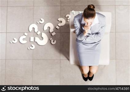 Thoughtful businesswoman. Top view of thoughtful businesswoman sitting on chair
