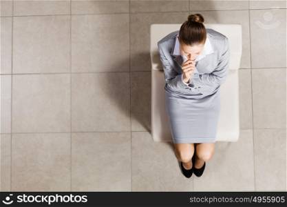 Thoughtful businesswoman. Top view of thoughtful businesswoman sitting on chair