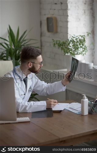 Thoughtful doctor holding chest and lungs xray in medical office